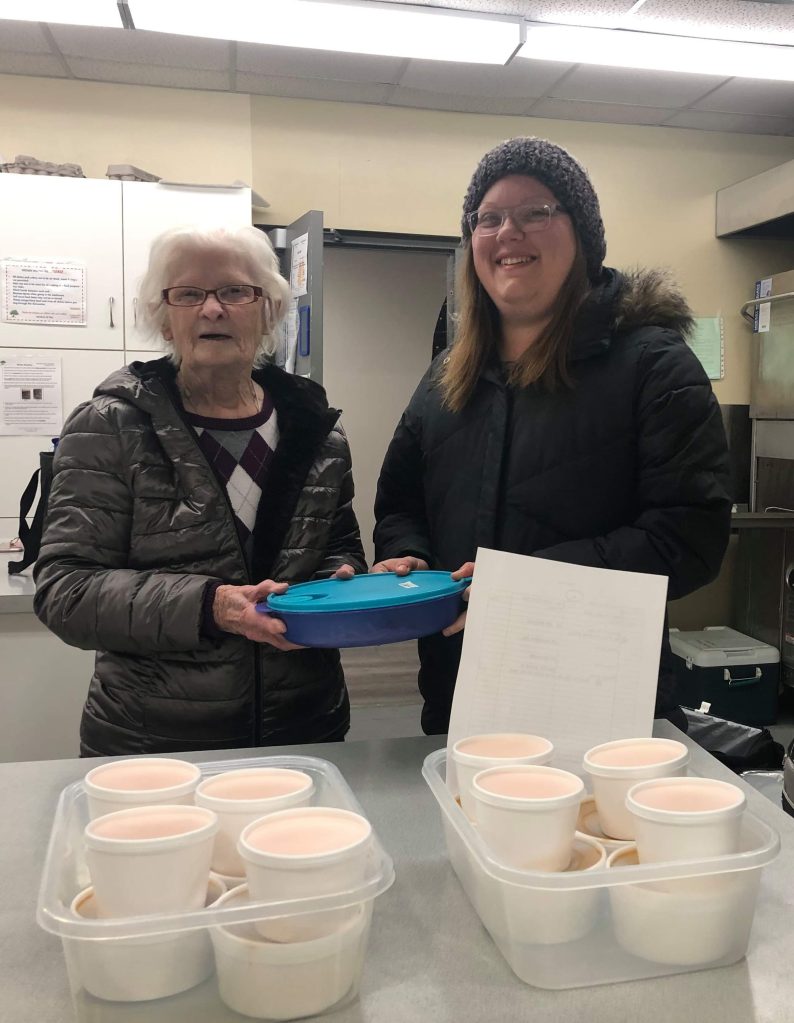 Jade Weedmark and Agnes picking up meals before beginning a Meals on Wheels delivery route through the Pat Porter Active Living Centre.